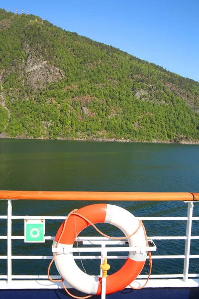 Deck of a ship & life ring as it cruises down the Sognefjord or Sognefjorden, nicknamed the King of the Fjords, is the largest and deepest fjord in Norway. Located in Vestland county in Western Norway.
