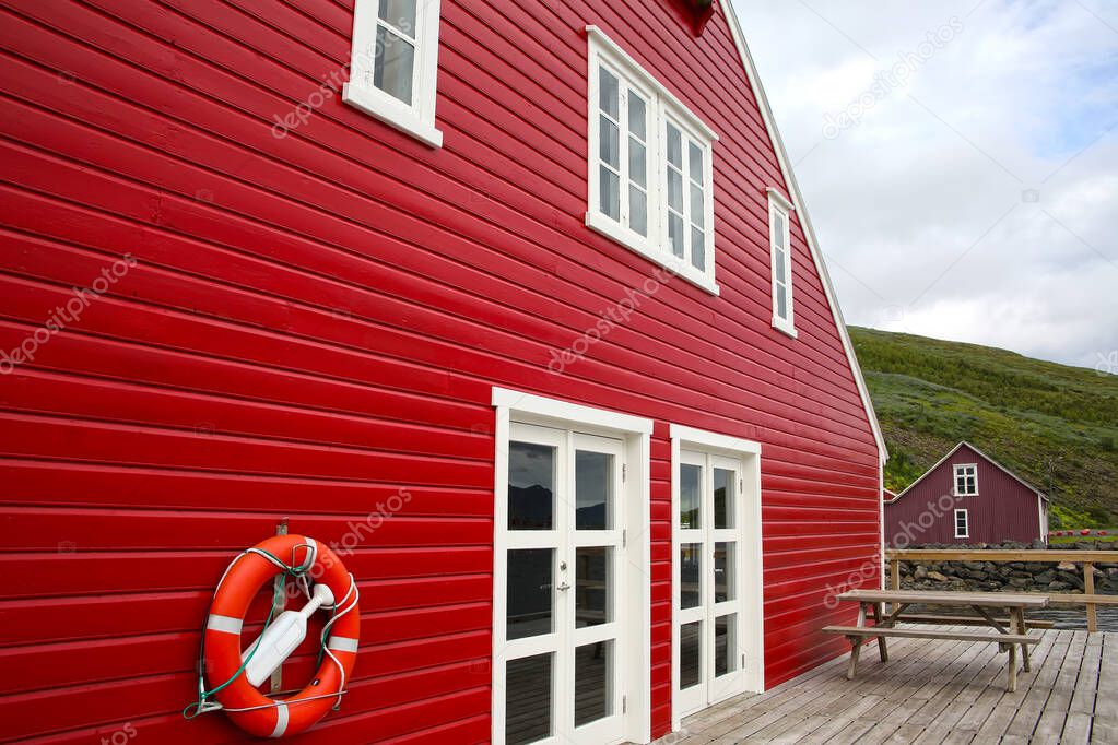 Traditional red painted wooden panel house with wooden slatted decking, Eskifjordur, East Iceland.