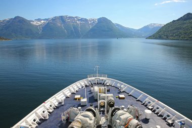 Geminin pruvası, güzel fiyorttan aşağı inerken su boyunca dağlar ve vilateler, Hardangerfjord, Norveç.