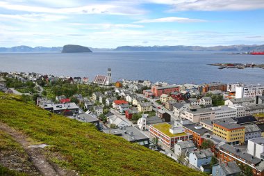 Şehir merkezinde Hammerfest kasabası ve arka planında dağlar ve fiyortlar olan katedral. Çekiç Festivali, 10.000 'den fazla nüfusuyla Norveç' in en kuzeyindeki kasabadır..