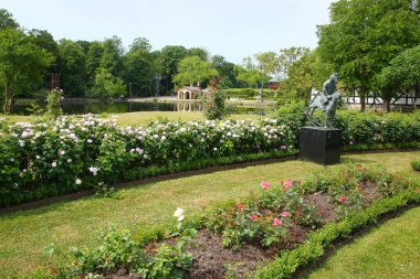 Geleneksel resmi halk bahçesi, Danimarka 'nın Funen adasının güneyinde, Kvaerndrup yakınlarında, arka planda bir göl bulunan yaz aylarında çiçek açar..