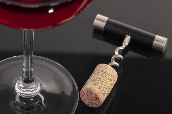 High angle view with shallow depth of field of a glass of red wine with a corkscrew. — Stock Photo, Image