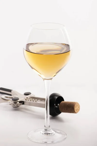 Hög vinkel vy med grunt skärpedjup av ett glas vitt vin med en korkskruv. Stockbild