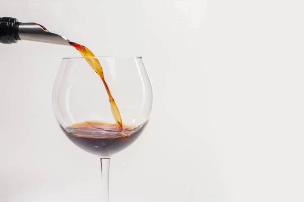 赤ワインをグラスに注ぐ。白い背景と柔らかい影の上に赤ワインのガラス。テキストの場所があります。. — ストック写真
