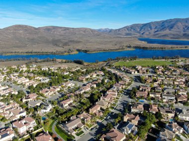 Güneşli bir günde arka planında büyük göl ve dağ olan özdeş yerleşim evinin havadan görüntüsü. 