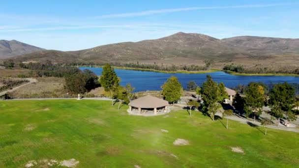 Aerial view of little park in front of Otay Lake Reservoir with blue sky and mountain — Stock Video