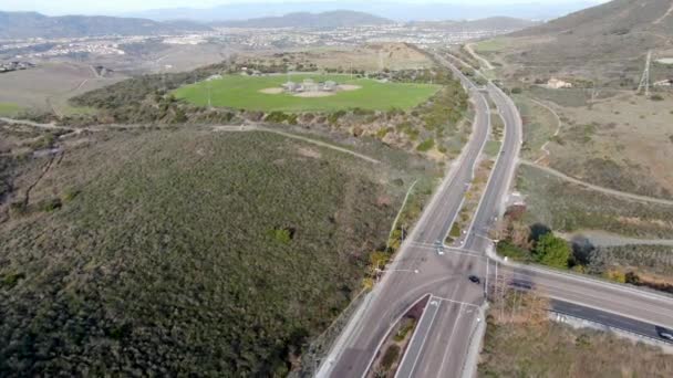 Vista aérea del campo de deportes de béisbol del parque comunitario junto a una pequeña carretera en un valle verde — Vídeo de stock