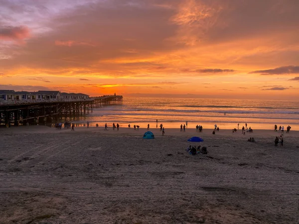 Pacific beach shoreline and pier during colorful sunset. — Stock Photo, Image