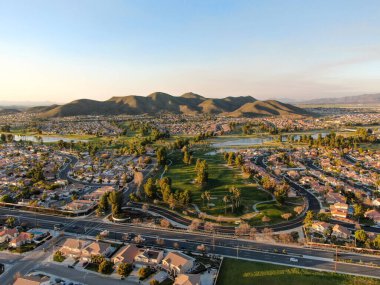 Gün batımında şehir evleri ve lüks villalarla çevrili golf sahasının havadan görünüşü, Temecula