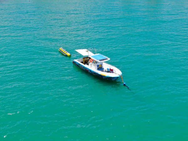 Barco de pesca deportiva con paseo en barco de plátano adjuntar en la parte posterior. En Praia do Forte playa — Foto de Stock
