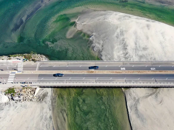 Автомобильное движение по небольшому мосту между двумя пляжами, река сливается с океаном — стоковое фото