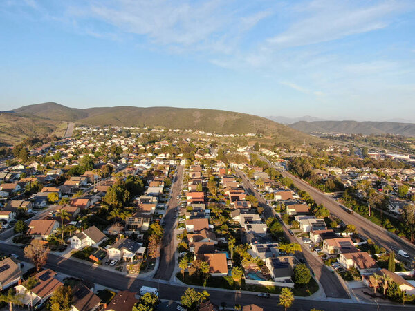 Aerial view of residential modern subdivision house neighborhood with mountain on the background during sunset time. South California, USA