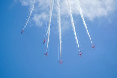 Mavi gökyüzünde beyaz dumanlı akrobatik bir uçak.