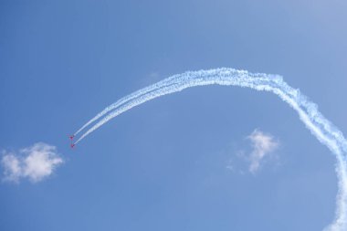 Mavi gökyüzünde akrobatik formasyon yapan bir uçak. Uçak fuarında uçaklar