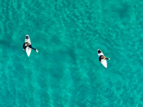 Вид с воздуха на серферов, ждущих, гребущих и наслаждающихся волнами в красивой голубой воде — стоковое фото