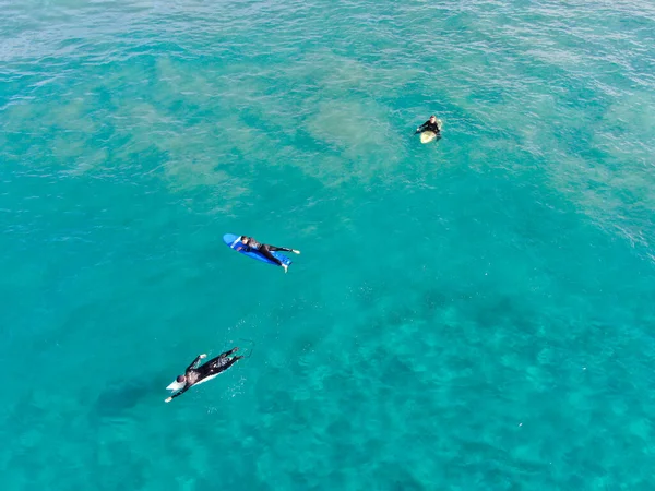 Vista aérea de surfistas esperando, remando e desfrutando de ondas em uma bela água azul — Fotografia de Stock