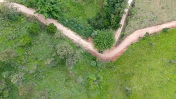 Flygfoto över bilen kör genom en liten grusväg i mitten av grön tropisk dal. — Stockvideo