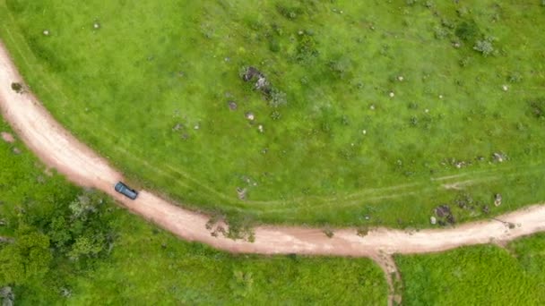 Flygfoto över bilen kör genom en liten grusväg i mitten av grön tropisk dal. — Stockvideo