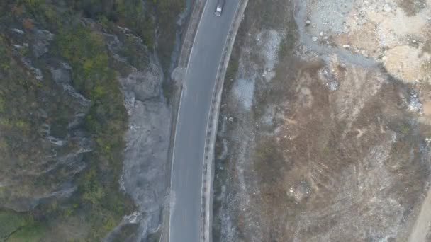 Vue aérienne d'une voiture blanche conduisant sur une petite route asphaltée dans une montagne sèche — Video