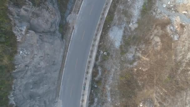 Vista aérea superior do carro branco dirigindo em uma pequena estrada de asfalto em uma montanha seca — Vídeo de Stock