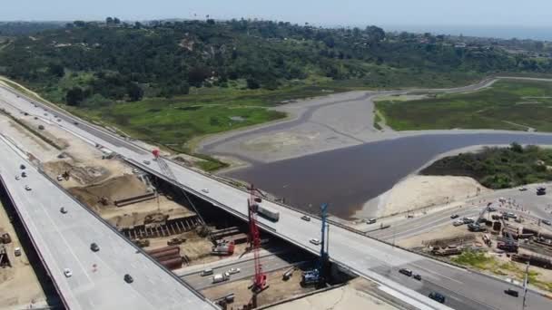 Vista aérea de la construcción de puentes de carretera sobre un pequeño río — Vídeo de stock