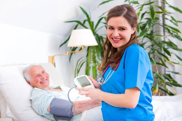 Loving caregiver measuring blood pressure — Stock Photo, Image