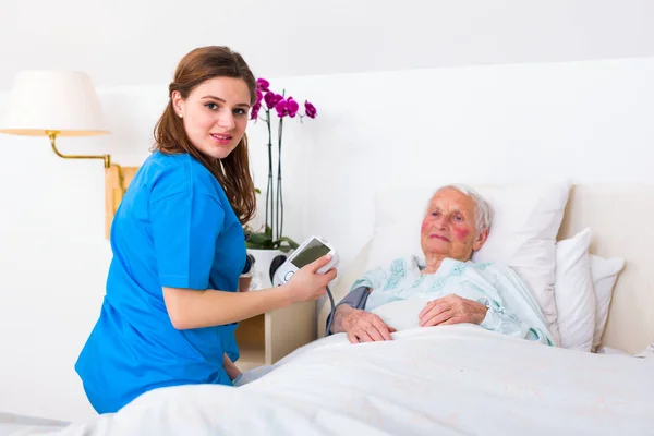 Caretaker measuring blood pressure — Stock Photo, Image