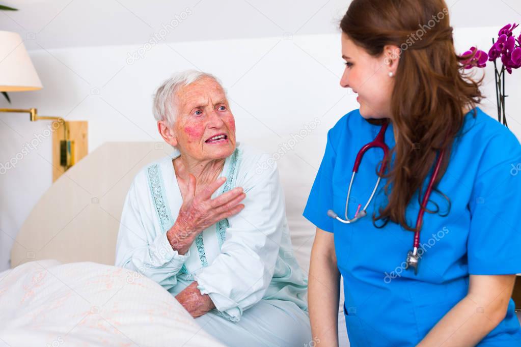 Kind nurse listening to senior sick woman