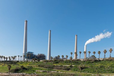 Mavi gökyüzüne karşı elektrik santrali bacalarından duman yükseliyor. Hadera, İsrail enerji santrali.