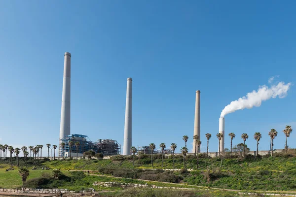 Mavi gökyüzüne karşı elektrik santrali bacalarından duman yükseliyor. Hadera, İsrail enerji santrali.