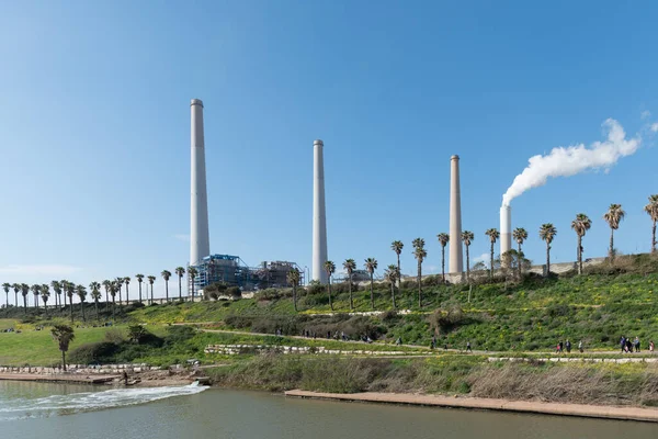 Mavi gökyüzüne karşı elektrik santrali bacalarından duman yükseliyor. Hadera, İsrail enerji santrali.