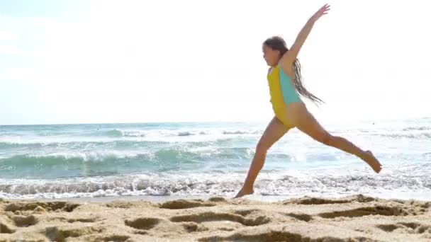 Koşma ve atlama kumsalda oynarken küçük kız — Stok video