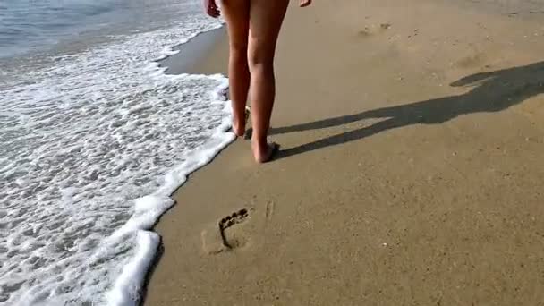 Criança / menina andando na praia deixando pegadas na areia, apenas pernas, câmera lenta — Vídeo de Stock