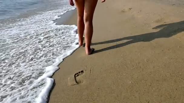 Bambino / ragazza che cammina sulla spiaggia lasciando impronte sulla sabbia, solo gambe, rallentatore — Video Stock