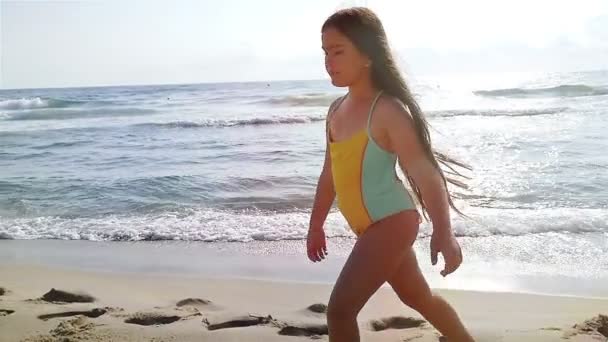 Zeitlupe eines süßen kleinen Mädchens im Badeanzug, das am Strand spielt — Stockvideo