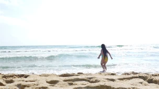 Αργή κίνηση του ένα χαριτωμένο κοριτσάκι με μαγιό που παίζει στην παραλία της θάλασσας — Αρχείο Βίντεο