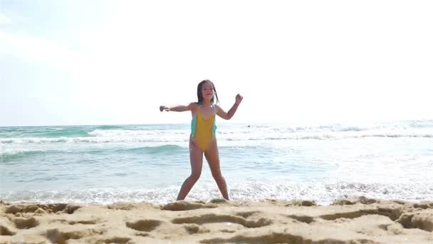 Slow motion of a cute little girl in swimsuit playing at the sea beach — Stock Video