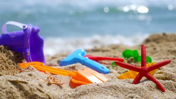 Песчаные игрушки на морском пляже, волны на заднем плане — стоковое видео