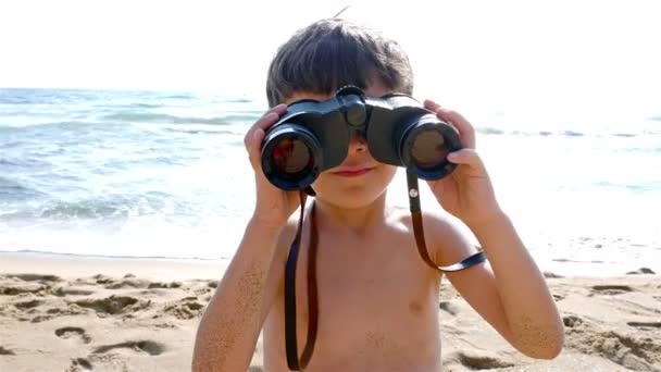 Ragazzino in costume da bagno utilizza binocoli per esplorare il mare — Video Stock