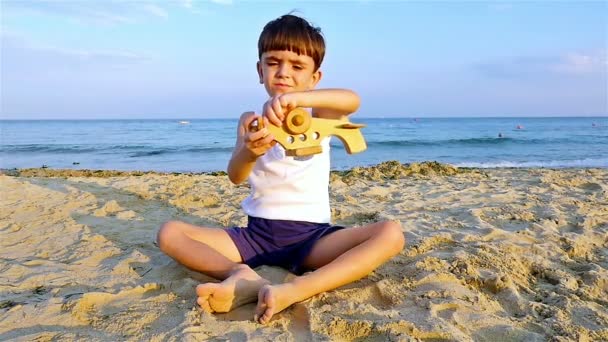 Kleine jongen spelen met speelgoed vliegtuig op het zee-strand, slow-motion — Stockvideo