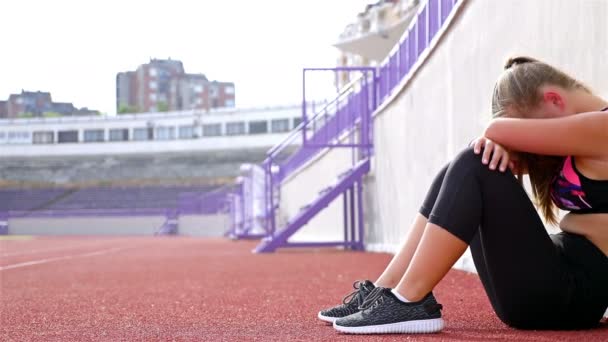 Genç kız atlet nefes alarak yorgun bitkin bir stadyum üzerinde çalıştırdıktan sonra hayal kırıklığına — Stok video