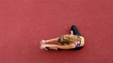 Genç kız sporcunun bir stadyum üzerinde çalıştırmadan önce germe Üstten Görünüm