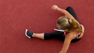 Genç kız sporcunun bir stadyum üzerinde çalıştırmadan önce germe Üstten Görünüm