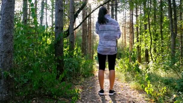 Câmera de rastreamento de mulher menina com fones de ouvido correndo correndo no parque, madeira, floresta — Vídeo de Stock