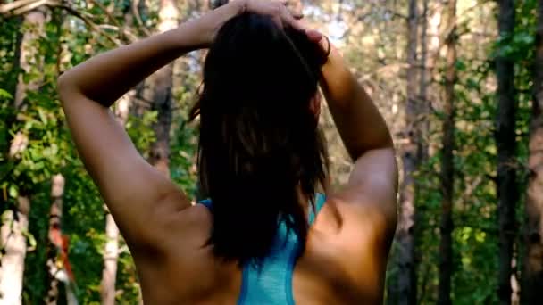 Tracking camera of woman girl tying her hair before running jogging in park, wood, forest — Stock video