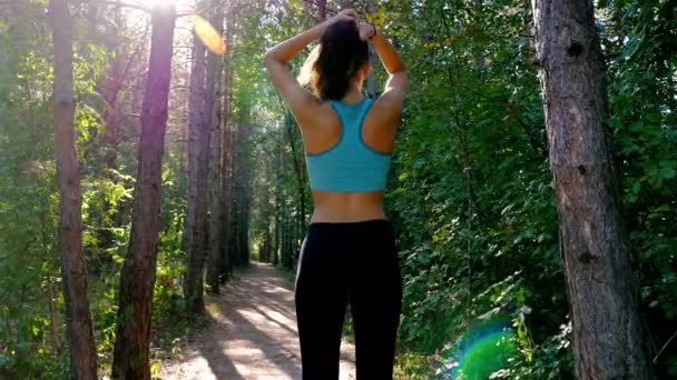 Tracking camera of woman girl tying her hair before running jogging in park, wood, forest — Stock video