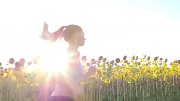 Tracking camera of woman girl with headphones running jogging in sunflower field — Αρχείο Βίντεο