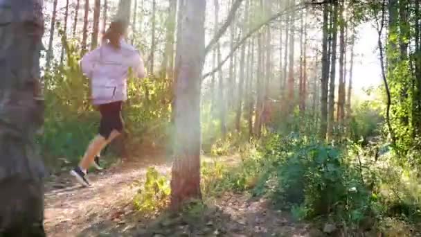 Tracking camera of woman girl with headphones running jogging in park, wood, forest — ストック動画