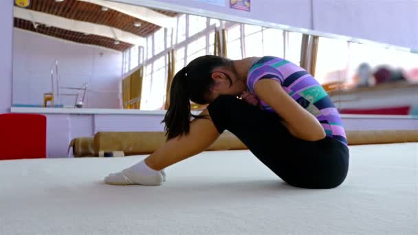 Female gymnast on the floor of a gym feeling pain — Stockvideo