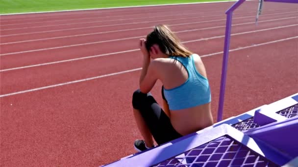 Desperate disappointed track runner athlete woman at a stadium, dolly — ストック動画